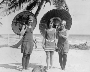Photograph of three women on a beach holding parasols, 1915.